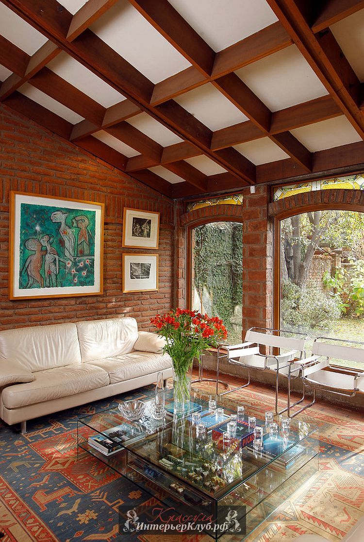 Арочные окна и потолочные балки приносят классическую элегантность в гостиную с кирпичной стеной