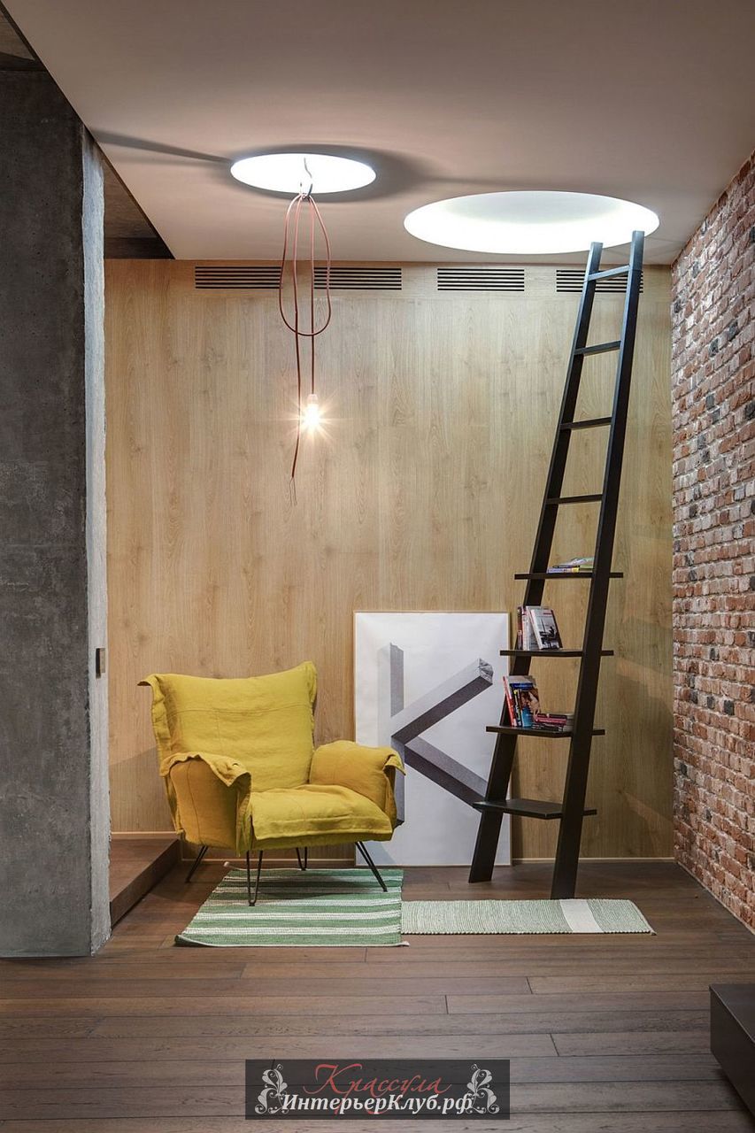 Уютное место для чтения - кирпичная и деревянная стена, лестница в качестве книжной полки и желтое кресло как цветовой акцент